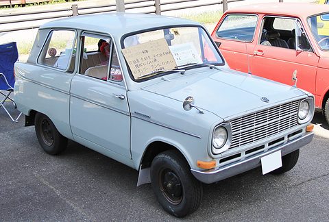 Pale blue small saloon with a white roof and a card in its windscreen, a red car behind. Opens a larger view