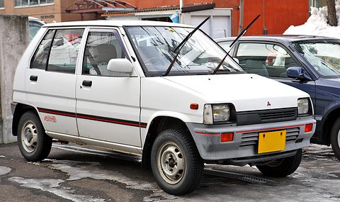 White small five-door hatchback with a red side stripe on a slushy car park. Opens a larger view