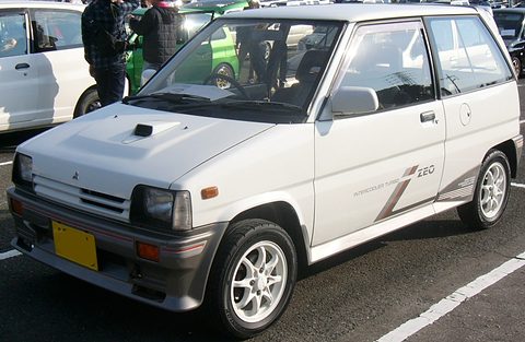 White small hatchback with a bonnet scoop and alloy wheels in a car park. Opens a larger view