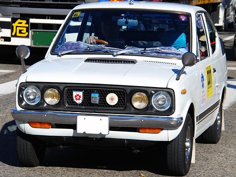 White small coupé seen from the front, with badges on the grille between four headlamps. Opens a larger view