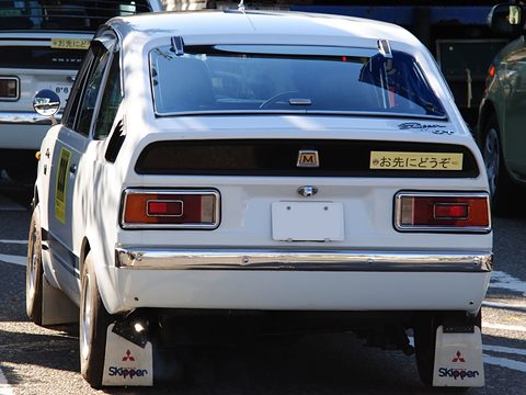 Rear view of a white coupé with wide tail lamps and Skipper mudflaps. Opens a larger view