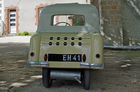 Rear of a cream coupé with two rows of round vents, a plate and a single exhaust. Opens a larger view