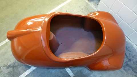 Orange moulded tub seen from above: a large oval cockpit opening and the seat moulding inside. Opens a larger view