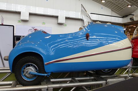 Side view of a blue and cream single-seat replica on a steel display rack. Opens a larger view
