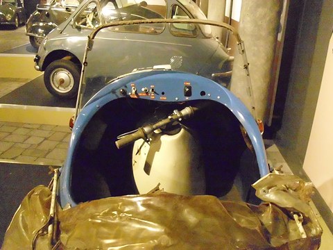 Looking down into a tiny blue tub: handlebar over a cream fuel tank, a switch panel and folded hood. Opens a larger view