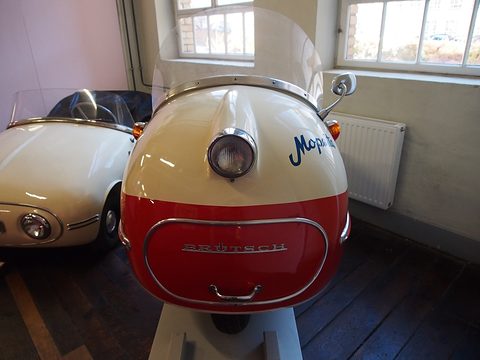 Cream and red nose of a single-seater with one round headlamp, Mopetta script and a chrome-framed oval panel. Opens a larger view