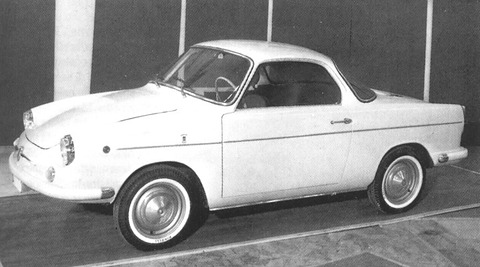A black-and-white side view of a small two-door coupé with whitewall tyres and a sloping rear window.