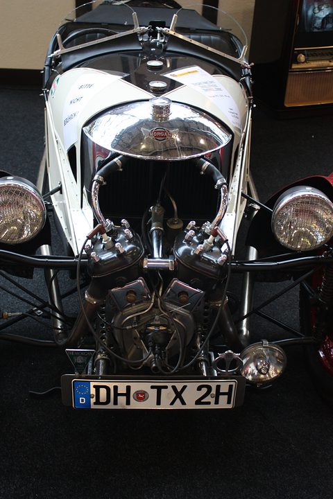 Front view of a white three-wheeler with a polished cowl, Matchless V-twin and two headlamps, a German plate below. Opens a larger view