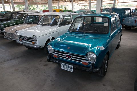A teal small saloon in front of a line of white and pale small saloons under a shed roof. Opens a larger view