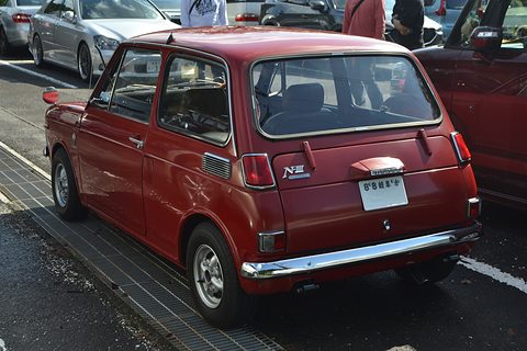 Rear three-quarter of a dark red small saloon with an N III badge, parked cars around. Opens a larger view