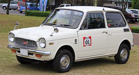 White small saloon on grass with a red-and-white 01 roundel on its door. Opens a larger view