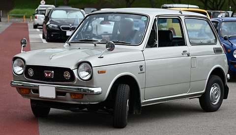 Pale grey small saloon on a red-and-grey tarmac lane, other cars behind. Opens a larger view