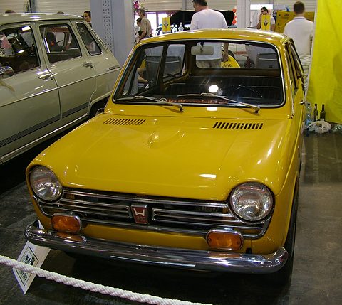 Yellow small saloon behind a rope on a polished floor, other cars and visitors behind. Opens a larger view