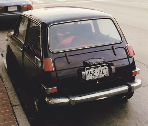 Rear view of a black small saloon with a Colorado plate, parked by a brick kerb. Opens a larger view