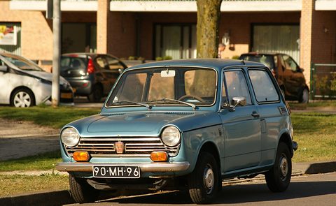 A small pale blue two-door saloon with round headlamps, a chrome bar grille with an H badge and amber indicators. Opens a larger view