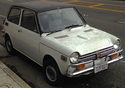 White small saloon with a black roof and faded paint parked at a kerb with a California plate. Opens a larger view