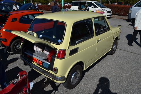 Rear of a cream small saloon with the boot lid lifted, a white people carrier behind. Opens a larger view