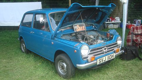 Blue small saloon with the bonnet raised and a SALE sign, parked on grass beside a gazebo. Opens a larger view