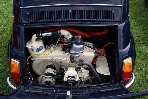 Rear engine bay of a dark blue Fiat 500 with a cream engine and cooling shroud and red hoses, seen from behind. Opens a larger view