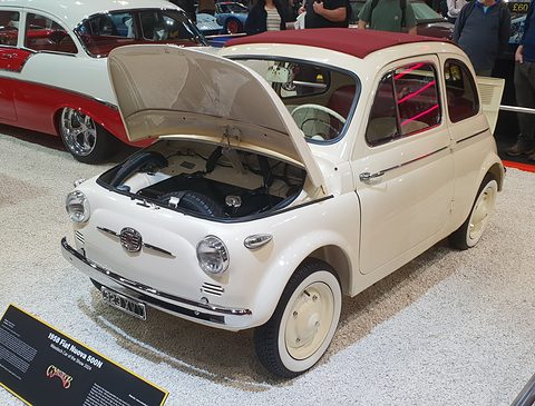 Cream Fiat 500 with its front lid open, a display board in front and visitors behind. Opens a larger view