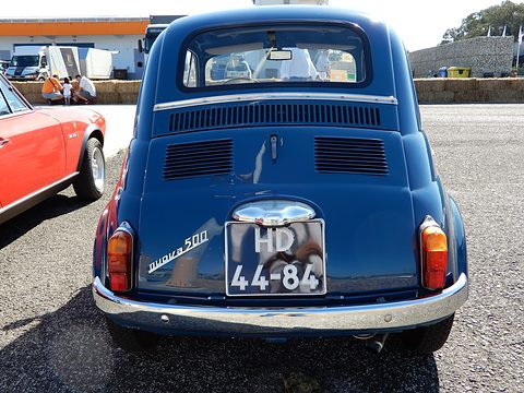 Rear of a blue Fiat 500 with louvred engine lid, chrome nuova 500 script and a black Portuguese plate. Opens a larger view