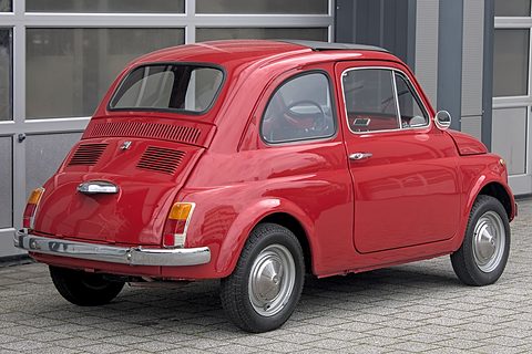 Red Fiat 500 from the rear left with a louvred engine lid and chrome bumper, on grey paving. Opens a larger view