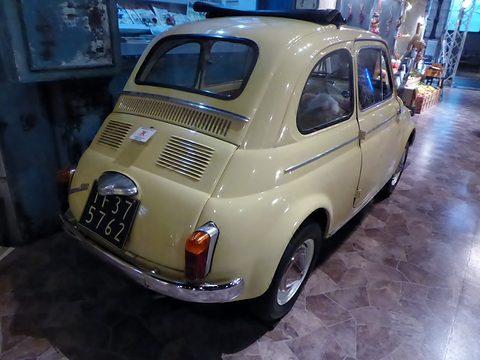 Cream Fiat 500 from the rear left with a louvred engine lid and black Italian plate, on a polished marble floor. Opens a larger view