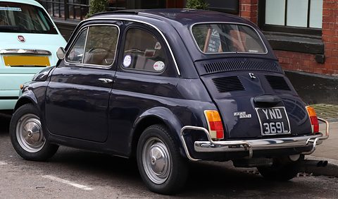 Black Fiat 500 from the rear right with tubular bumper guards and a British plate, a pale blue modern 500 in front. Opens a larger view