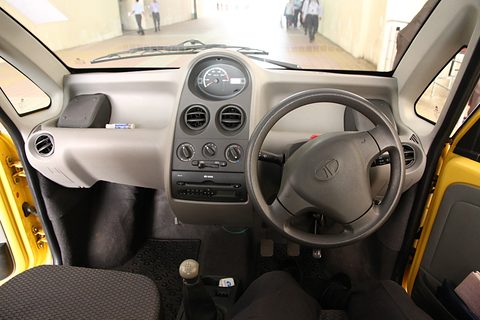 Grey dashboard with a single round speedometer in the middle, a three-spoke steering wheel on the right and yellow door frames. Opens a larger view