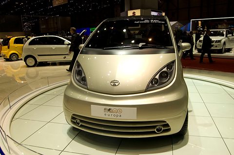 Front of a champagne-coloured small hatchback with a slatted grille and a Nano Europa plate on a white turntable. Opens a larger view