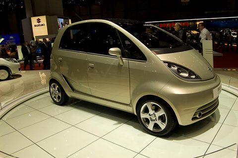 Champagne-coloured small hatchback with alloy wheels on a white turntable in a show hall. Opens a larger view
