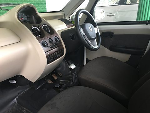Beige and black dashboard with round vents, a three-spoke steering wheel and dark seats, seen through the open door. Opens a larger view