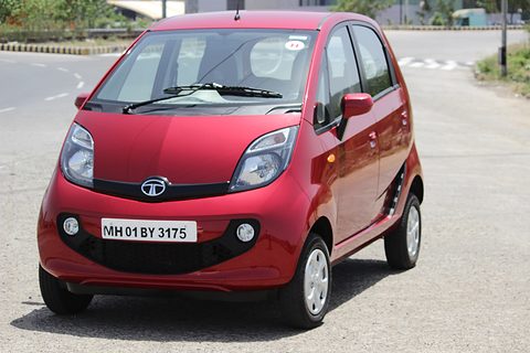 Red small hatchback with a black grille bar and fog lamps parked on a wide empty road. Opens a larger view