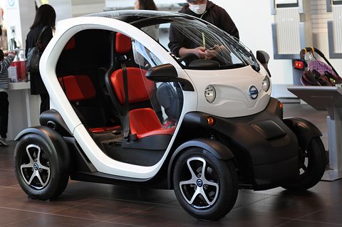 White and black tandem two-seat electric quadricycle with red seats and open sides on a gallery floor. Opens a larger view