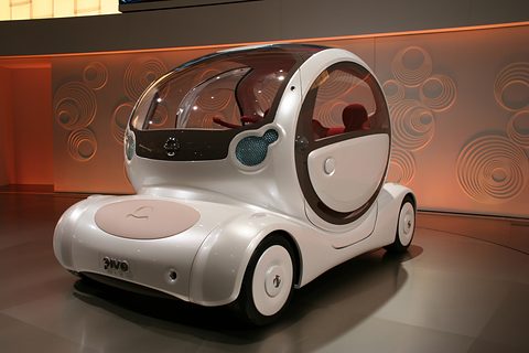White bubble-shaped concept with a domed glass cabin and round door, seen from behind on a stand. Opens a larger view