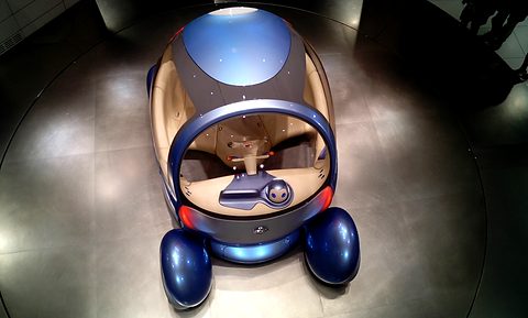Blue and cream bubble concept with separate wheel pods and a small robot head on the dashboard, seen from above. Opens a larger view