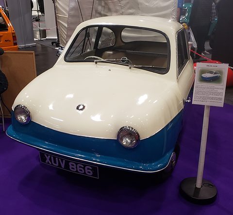 White and blue microcar with round headlamps and registration XUV 866, information stand beside it. Opens a larger view
