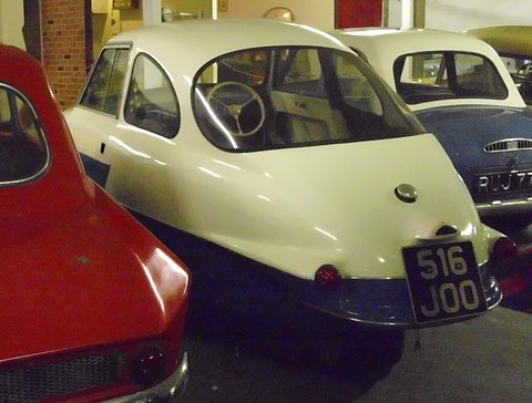 Back of a cream and blue microcar with a rounded tail and registration 516 JOO between other cars. Opens a larger view