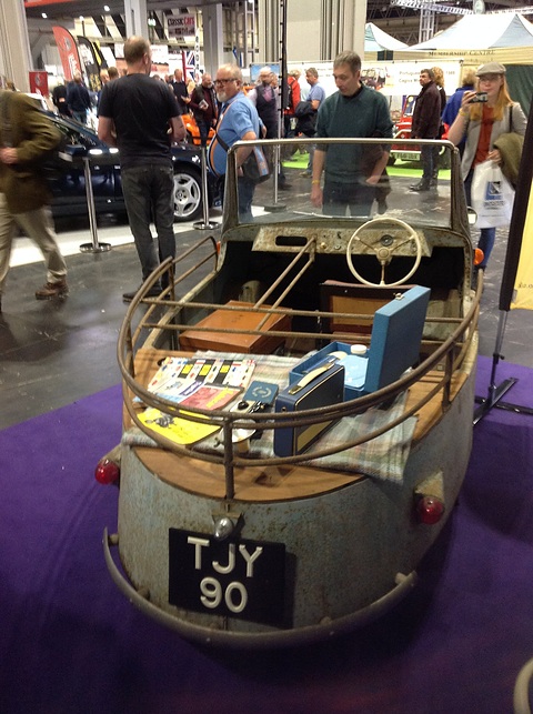 Unrestored pale blue open three-wheeler with tubular rails around a load bed, registration TJY 90. Opens a larger view