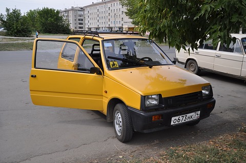 Yellow small hatchback with its driver’s door open and a roof rack, a disabled-driver sticker in the windscreen. Opens a larger view