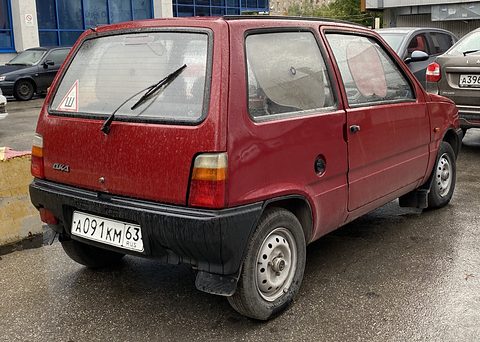 Rear quarter of a small red hatchback with a black bumper, rear wiper and a Russian plate, in a car park. Opens a larger view