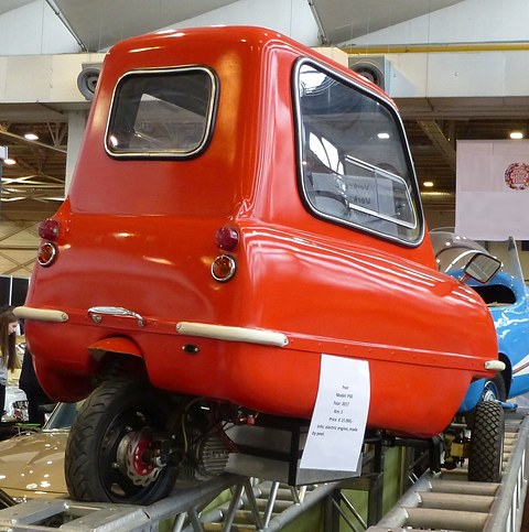 Tiny red car from behind on a metal display rack with a sale notice in its window. Opens a larger view