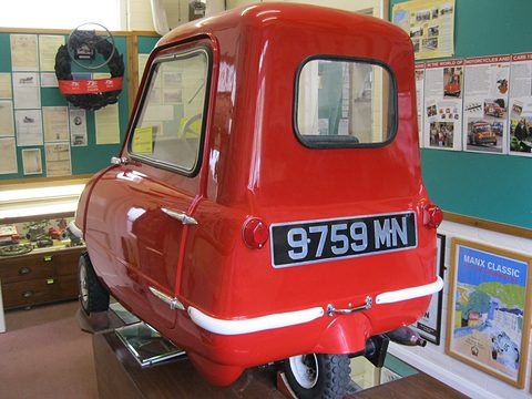 Tiny red car from behind with a window in its back and a plate reading 9759 MN