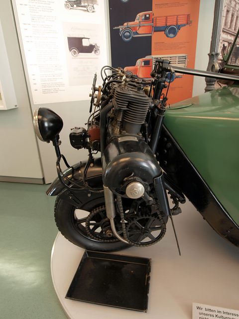 Close view of a finned engine and lamp mounted on the fork of a single front wheel. Opens a larger view