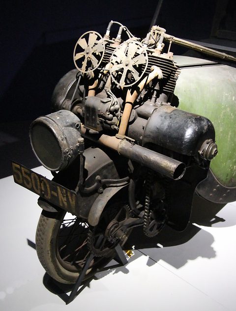 Head-on view of a finned engine with two cooling fans and a lamp mounted above a single wheel. Opens a larger view