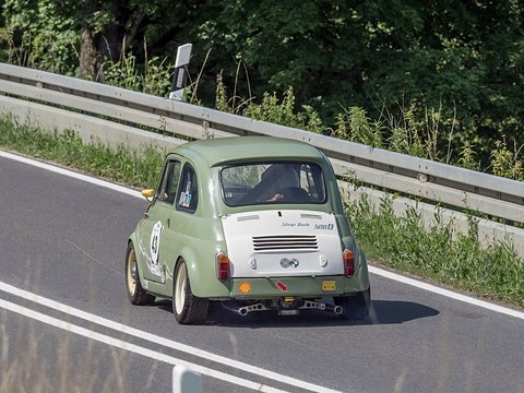 Pale green small car from behind with a white engine lid, race number 43 and a Shell sticker, beside a crash barrier. Opens a larger view