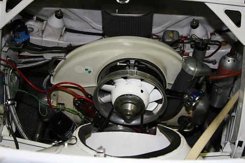 Engine bay with a white fan shroud bearing Steyr and Puch badges, a large fan, air filter and wiring.