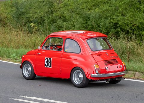 Red small car with number 38 on the door, seen from behind on a road, twin exhaust pipes under the bumper. Opens a larger view