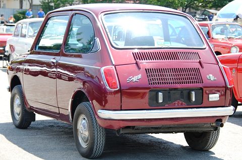 Rear three-quarter of a maroon small saloon with louvred engine lid and a GL badge, other cars behind. Opens a larger view