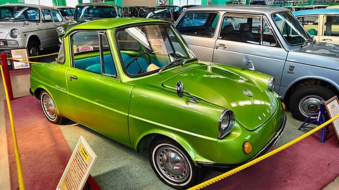 Lime-green coupé with whitewall tyres inside a yellow rope, a silver saloon beside it. Opens a larger view